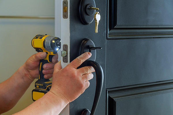 Our Pit Pro Handyman changing door locks on a client's door. Using a DeWalt drill and screw bit to install a new front door lock set. 