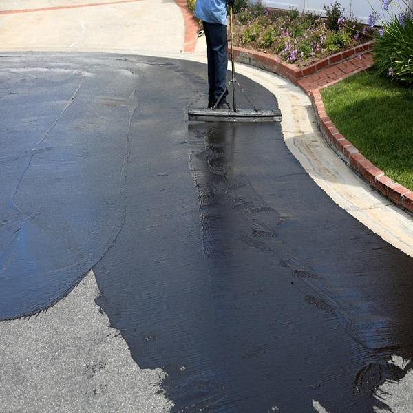 Asphalt coating of a driveway in Pittsburgh using a squeegee to spread the coating 