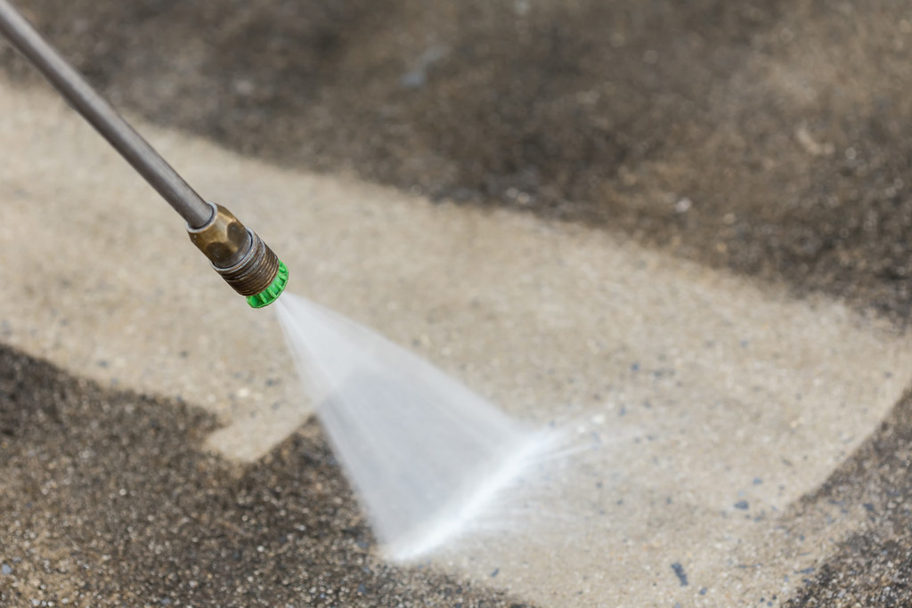 Power washer spray close up showing a cleaned area in the middle of mildew covered concrete sidewalk in Pittsburgh 