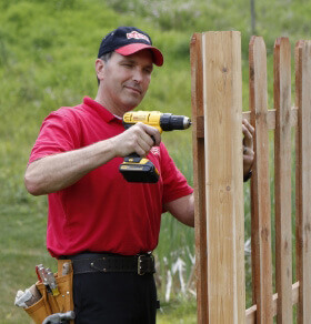 A Pit Pro Handyman installing a new cedar fence in Cranberry Township Pennsylvania. Man with drill screwing a fence panel together. 