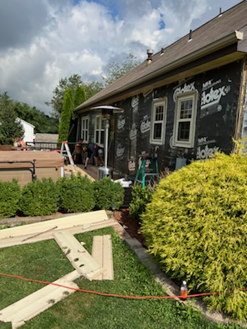 Tearing off fiber board siding in preparation for vinyl installation. 