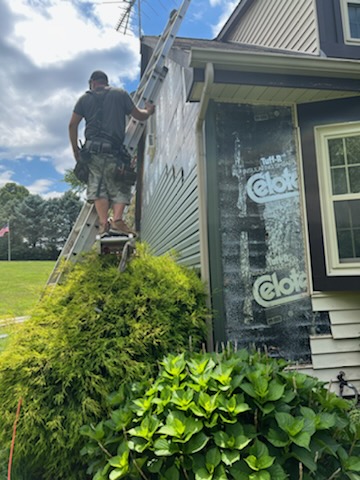 Pit Pro Handyman on a ladder installing sea foam green vinyl siding in Cranberry Township PA