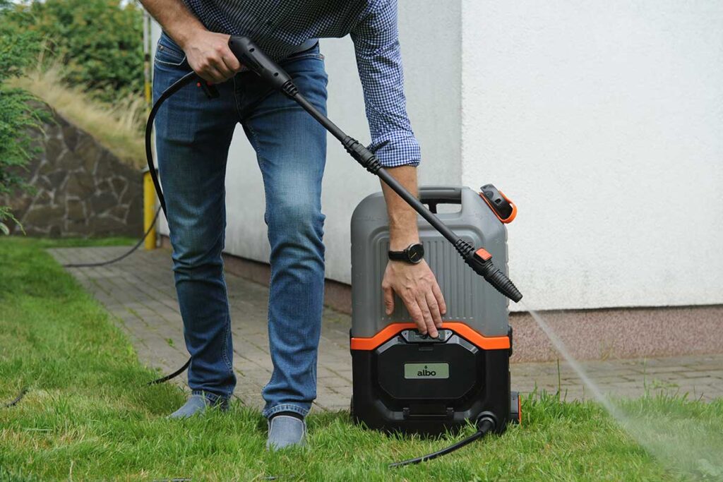 Pit Pro Handyman using a battery operated power washer to wash delicate stucco cladding
