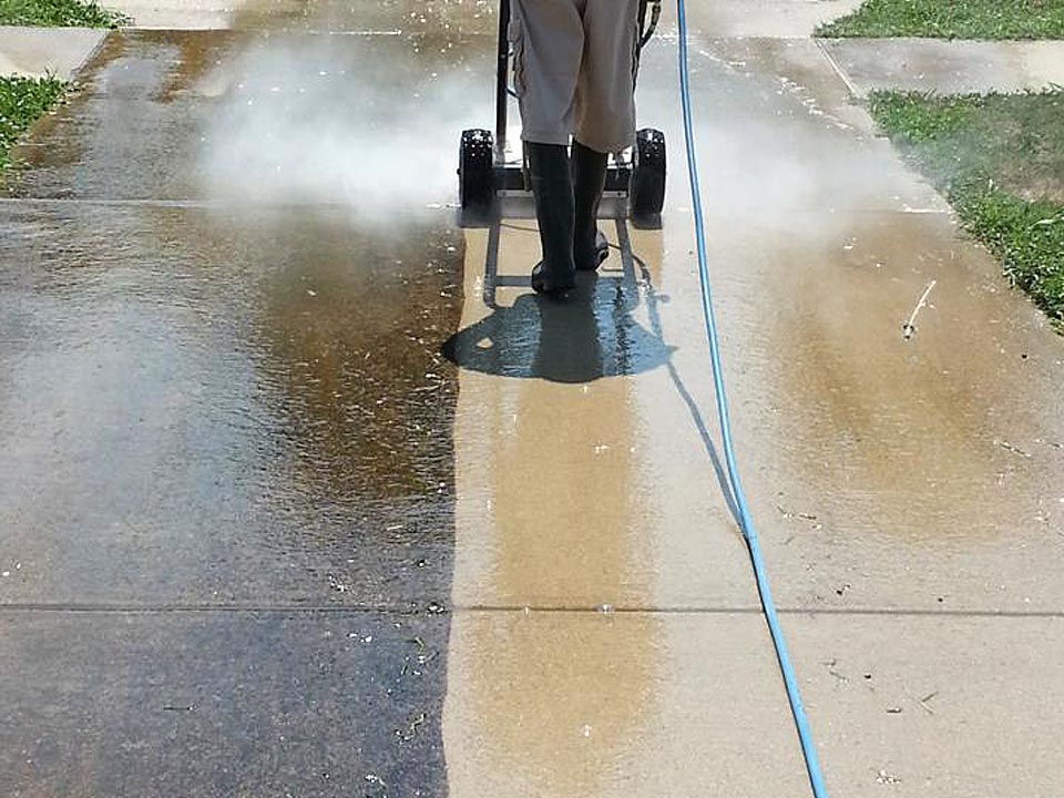 a concrete driveway with the left half slippery and mildew covered and the righ half being pressure washed and clean and skid free 